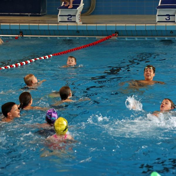 Damian Wierling schwimmt mit Kindern im Wasser